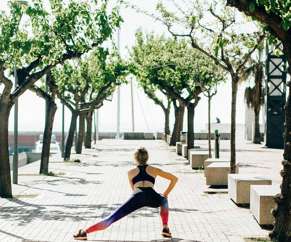 Person stretching gently outdoors during a sunny day.